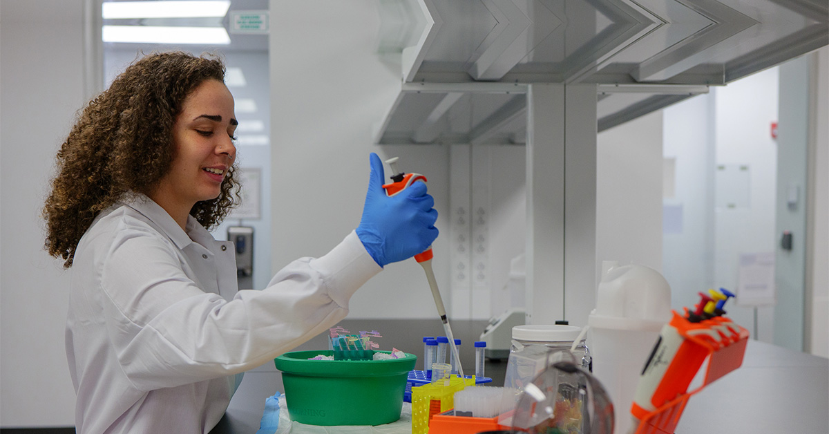 Woman with a large syringe putting liquid into a test tube, doing research