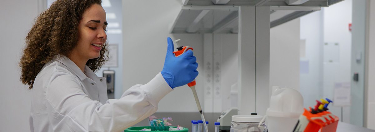 Woman with a large syringe putting liquid into a test tube, doing research