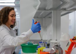 Woman with a large syringe putting liquid into a test tube, doing research