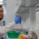 Woman with a large syringe putting liquid into a test tube, doing research