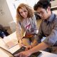 A professor and a student work together on a laptop in a classroom