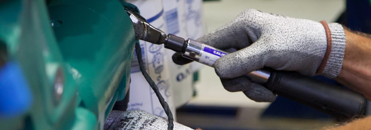 Close up of two hands using a wrench on a piece of equipment