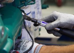 Close up of two hands using a wrench on a piece of equipment