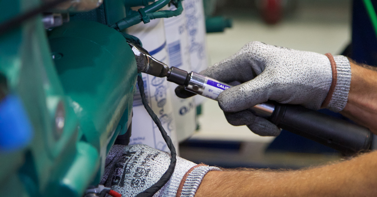 Close up of two hands using a wrench on a piece of equipment